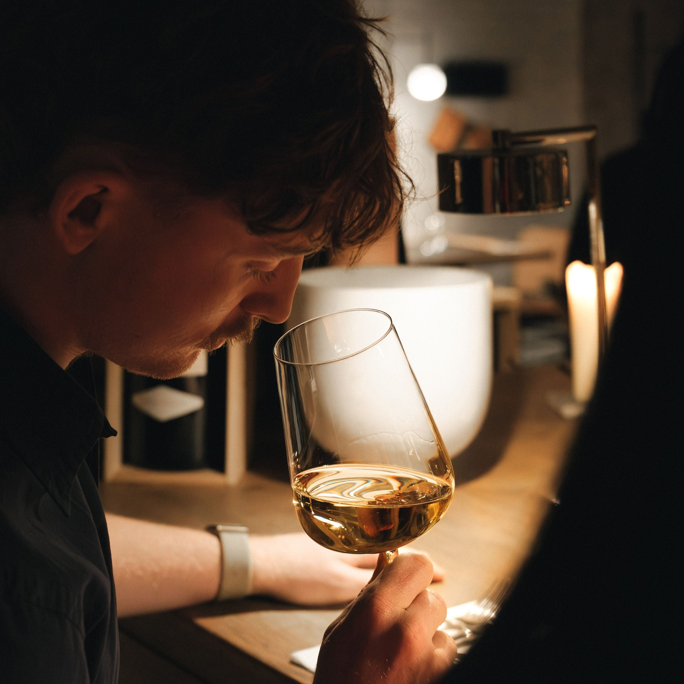 Person holding a glass of wine in a dimly lit bar setting